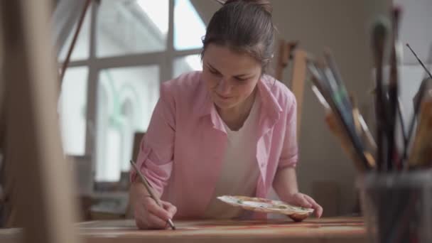 Arte, creatividad, afición y concepto de ocupación creativa. Dar vida a la creatividad. Una mujer pintando en un estudio de arte. Atractiva pintura de artista femenina en taller. Mujer hobby, actividad, profesión. — Vídeo de stock