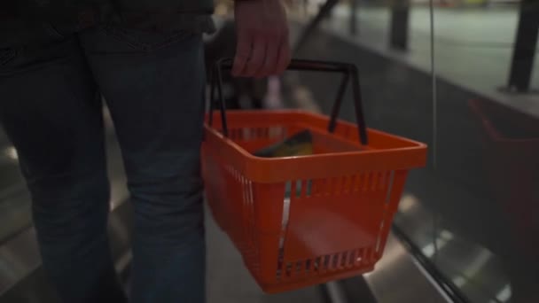 Man i skyddsmask med shoppingkorg i händerna flyttar rulltrappa i stora livsmedelsaffär. Unge far under karantänen handlar med coronavirus i mataffären. Ingen mask ingen ingång. Avdelning 19 — Stockvideo