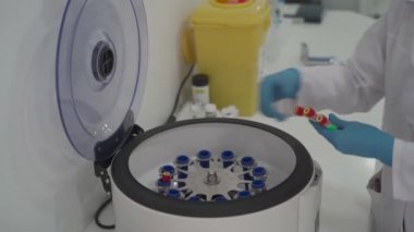 Trombosit zengini plazma hazırlığı. Elleri kanlı tüp. Santrifüj. Doktor ya da laboratuvar teknisyeni kan örneklerini santrifüje koyuyor.