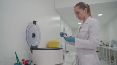 Bir tıbbi laboratuvar teknisyeni analiz için serum örneklerini makineye koyar. Hastanedeki kanın biyokimyasal analizi için gerekli ekipman
