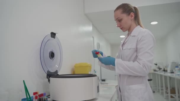 Um técnico de laboratório médico coloca amostras de soro em uma máquina para análise. Equipamento para análise bioquímica automática de sangue em um hospital — Vídeo de Stock