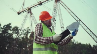 Güç sistemleri mühendisi geldi. Bir mühendis cep telefonuyla konuşuyor ve verileri bir elektrik hattı ağıyla karşılaştırıyor.