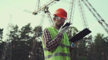Bir elektrik mühendisi çalışıyor. Telefonla konuş. Güç şebekesini kontrol ediyorum. Enerji. Sanayi
