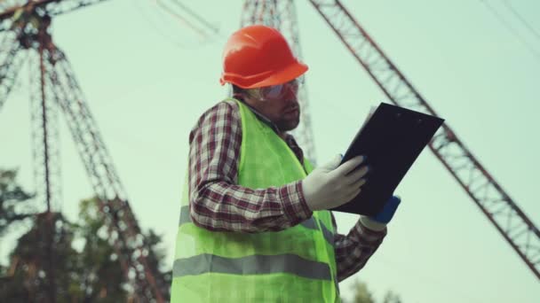 Alandaki bir tesiste çalışan bir elektrik mühendisi. Telefonda konuşmak ve elektrik şebekelerini kontrol etmek.. — Stok video