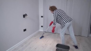İnsanlar, ev işleri ve ev işleri konsepti. Üst düzey kadın yerleri paspaslıyor. Evde yerleri paspaslayan güzel bir yetişkin kadın.