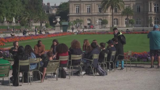 4 september 2021, Parijs. Frankrijk. De Luxemburgse Tuinen en studenten zitten op parkstoelen en hebben een docent tijdens hun studie — Stockvideo
