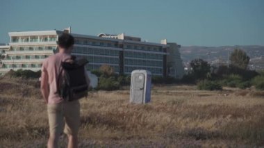 Sırt çantalı bir erkek yolcu Kıbrıs 'taki bir tarlada taşınabilir plastik bir tuvalete gidiyor. Doğada yalnız ve kuru bir dolap..