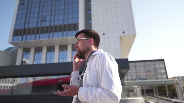 Врач Белом Халате Говорит Мобильному Телефону Перед Клиникой Врач Снаружи — стоковое видео