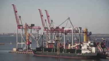 Odessa 'daki kargo konteynırı terminali. Limanda çalışan vinçleri olan kargo iskelesi. Vinç köprüsü altında, Odessa, Ukrayna 'da büyük bir kargo gemisi. Konteynır ihracatı lojistik, kargo limanı
