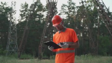 Elektrik istasyonunda çalışan bir işçi telsizle yürür ve rapor verir. Çalışan bir yerin arka planında çalışan bir panodaki bilgileri doğrular.