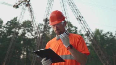 Elektrik istasyonunda çalışan bir işçi telsizle yürür ve rapor verir. Çalışan bir yerin arka planında çalışan bir panodaki bilgileri doğrular.