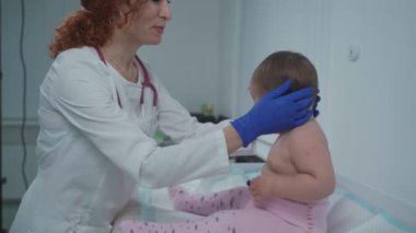 Kızıl saçlı kadın doktor, küçük çocuğu modern bir klinikte bir yıldan kısa bir süre muayene ediyor. Hastanede muayene sırasında çocuk doktoruydum. Çocuk sağlık hizmetleri. Çocuk için teşhis ve tedavi.