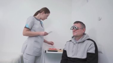Vizyon düzeltmesi. Gözlük seçimi. Modern oftalmolog muayenehanesinde doktor görüşü kontrol ederken profesyonel hasta yüzü çerçeveleri. Optometrist gözlük reçetesini kontrol ediyor.