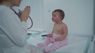 Kızıl saçlı kadın doktor, küçük çocuğu modern bir klinikte bir yıldan kısa bir süre muayene ediyor. Hastanede muayene sırasında çocuk doktoruydum. Çocuk sağlık hizmetleri. Çocuk için teşhis ve tedavi.