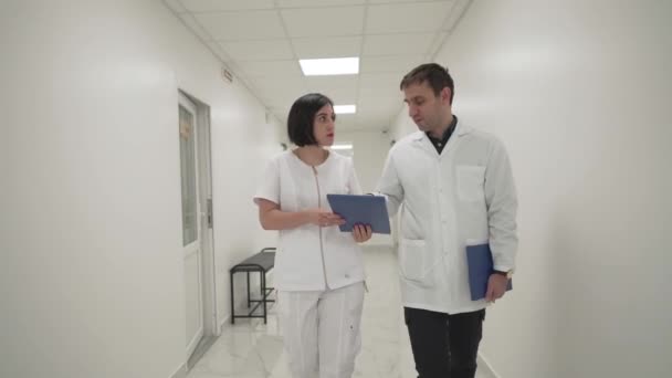 Dwóch Lekarzy Mężczyzna Kobieta Omawiających Akta Sprawy Dokumenty Medyczne Idących — Wideo stockowe