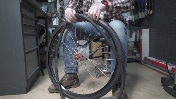 自転車屋で自転車のチューブとタイヤを交換します 車輪を固定する作業中の自転車修理工 自転車屋で働いている自転車整備士 サービスと自転車の修理とメンテナンス 中小企業 — ストック動画