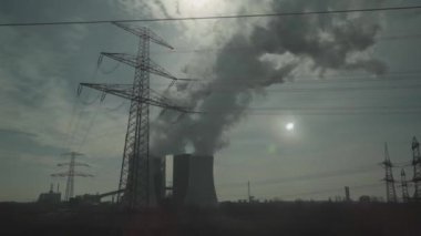Almanya 'daki fabrikalar ve termik santrallerden ekoloji ve hava kirliliği konuları. Güneşli bir havada Bavyera 'daki bir bitkinin baca borularının tren penceresinden görüntüsü. Kömür santralinden duman geliyor.