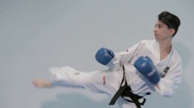 Kadın tekvando dövüşçüsü gölge boksu yumrukları ve tekmeler eğitiyor. Beyaz kimono giyen ve dövüş sanatları tekmesi atan bir kız. Kimonolu kadın tekvando çalışıyor. Ukrayna, Kiev 20 Mart 2017.