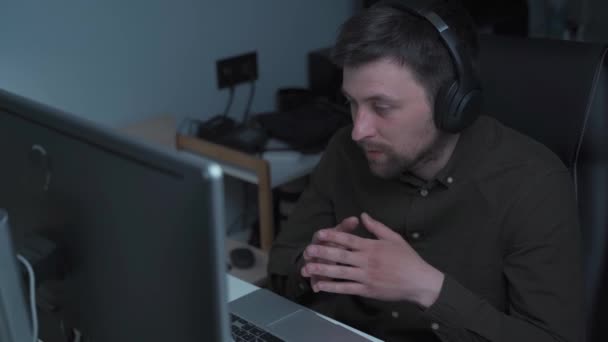 Skupiony Mężczyzna Noszący Słuchawki Trzymający Wideo Rozmowy Klientami Przy Komputerze — Wideo stockowe