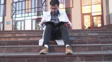 Eğitim, bilim, sağlık ve tıp kavramı. Tıp öğrencileri dışarıda merdivenlerde oturuyor, ders çalışıyor, ödev yapıyor, sınavlara ve sınavlara hazırlanıyor. Kampüsün dışında oturan öğrenci.