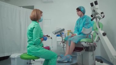 Modern bir klinikte jinekoloğuyla görüşen hasta jinekolog koltuğunda oturuyor. Kadın sağlığı. Doktorların muayenehanesinde jinekoloğun hastası.