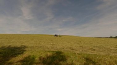 The theme of farming, agricultural farming in the Bavarian region of Germany in the summer. A farmer cultivates the land with the help of farm equipment. Mowing grass for hay