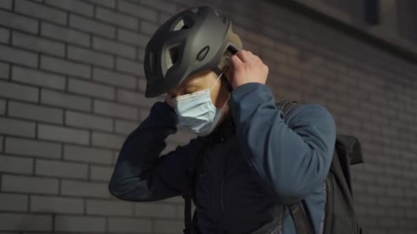 Man Cycling Puts Protective Mask Helmet Starts Riding His Bike — Vídeo de stock