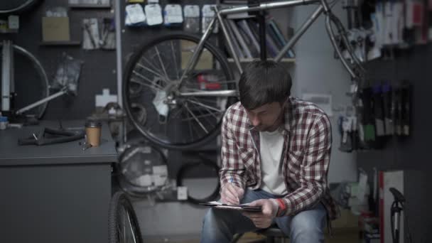 Tired Bike Shop Owner Fills Out Paperwork Does Calculations Irs — Αρχείο Βίντεο