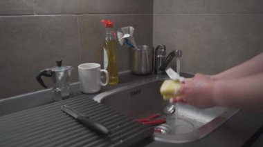 Ev temizliği, ev işleri. Mutfak lavabosunda bulaşık ve mutfak aletleri. Evde bulaşık yıkayan bir kadın. Çok fazla su kullanıyorsun. Sürdürülemez kaynak tüketimi kavramı