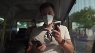 Man sits on bus wearing protective mask ffp2 uses smartphone in Germany, Munich. Passenger in protective mask in public transport and surfing Internet. Coronovirus rules of personal protection 