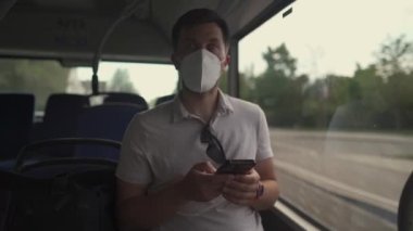 Passenger in ffp2 mask is on bus in Munich, browsing the Internet on mobile phone. Coronovirus regulations in Germany. Personal hygiene. Man on public transport using mobile app. Travel safely 