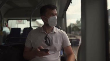 Man sits on bus wearing protective mask ffp2 uses smartphone in Germany, Munich. Passenger in protective mask in public transport and surfing Internet. Coronovirus rules of personal protection 