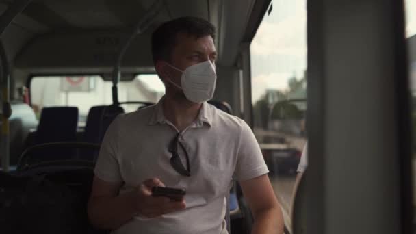 Άνθρωπος Κάθεται Στο Λεωφορείο Φορώντας Προστατευτική Μάσκα Ffp2 Χρησιμοποιεί Smartphone — Αρχείο Βίντεο