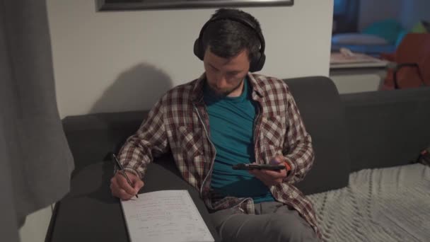 Male Student Uses Smartphone Headphones Home While Studying Online Taking — Stock Video