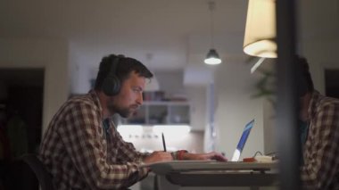 Student communicates online with teacher, uses headphones and laptop at home, writes notes, prepares for university test, college examination, watches educational webinar. Online education concept. 