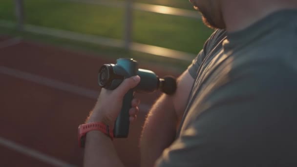 Athletic Male Massages Muscles Hand Massage Gun Recovering Stadium Running — Vídeos de Stock