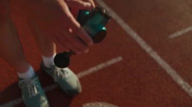 A male athlete massages muscles and tendons with a massage percussion device after a workout at the stadium. Sportsman uses electric massager gun in hand massaging the muscle. Sports recovery concept
