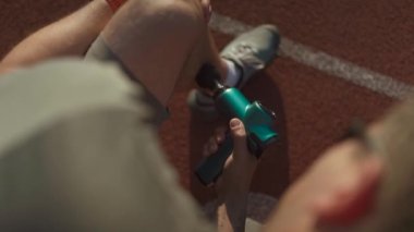 Athlete massages with percussion therapy gun to relieve pain of muscle aches after workout. Man massages his body with massage percussion device after training session. Muscle warming up with massager