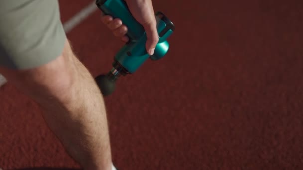 Male Athlete Massages Muscles Tendons Massage Percussion Device Workout Stadium — Vídeo de Stock
