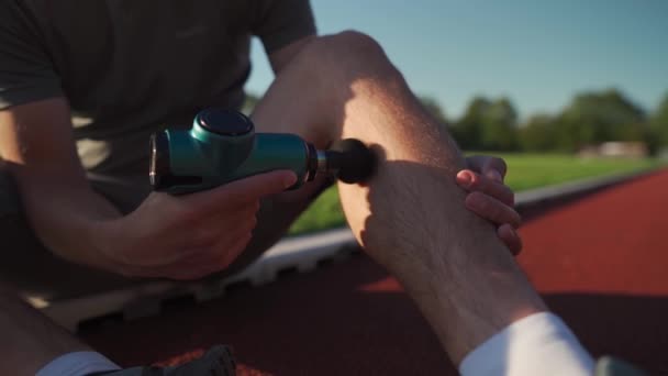 Athletic Male Massages Muscles Hand Massage Gun Recovering Stadium Running — Stock video