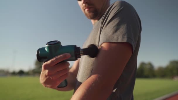 Athletic Male Massages Muscles Hand Massage Gun Recovering Stadium Running — Stock video