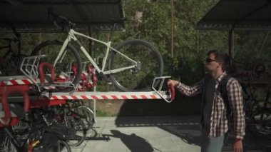 Adam bisikletini Münih, Almanya 'da iki katlı bir bisiklet parkına park ediyor. Çift katlı bisiklet parkı. Bisikletçi bisikletini ikiye bölünmüş bir bisiklet parkına park ediyor. Altyapı döngüsü