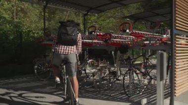 Bir adam bisikletini Almanya 'nın Münih kentindeki çok katlı modern bir bisiklet parkına park ediyor. Bisikletçi, iki kattaki park yerinin dışında bisiklet kenti kullanıyor. Bir erkek bisikletini iki sıra halinde park yerine koyar.