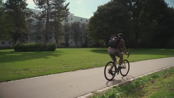 Hezký Hipster Batohem Košilí Letním Slunném Počasí Projíždí Městským Parkem — Stock video