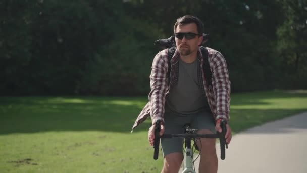 셔츠를 배낭을 사람은 자전거를 자전거를 정원의 자전거 도로를 달린다 자전거를 — 비디오