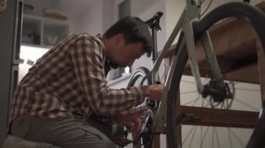Adam evde bisiklet tamir ediyor. Erkek evde bisikletini tamir eder. Adam evlerinde adet döngüsünü ayarlıyor. Küçük bir dairede bisiklet kurmak. Küçük bir stüdyo odasında bir döngü ayarlıyorum.