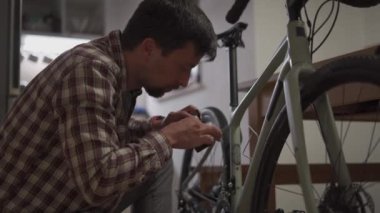 Adam evde bisiklet tamir ediyor. Erkek evde bisikletini tamir eder. Adam evlerinde adet döngüsünü ayarlıyor. Küçük bir dairede bisiklet kurmak. Küçük bir stüdyo odasında bir döngü ayarlıyorum.