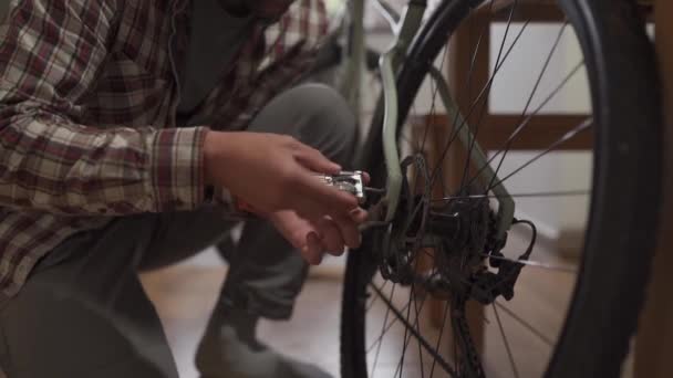 若い男が自宅のスタジオアパートに自転車のアクセサリーをインストールします 男は家で自転車をセットアップします 自宅の砂利の自転車で男性の固定自転車 新しい季節のための自転車の修理と準備の概念 — ストック動画