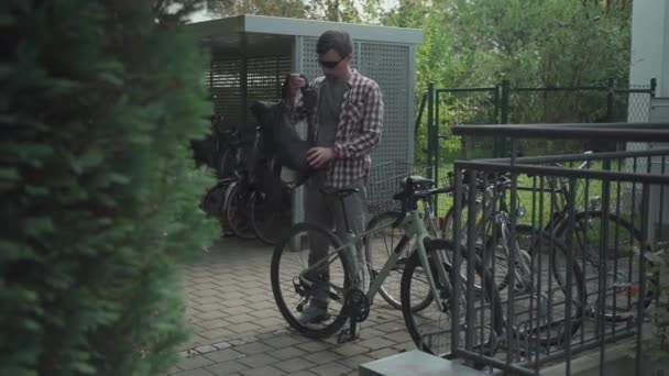サイクリストパークとドイツの自宅外の自転車駐車場で彼の自転車をロックします 中庭の駐車場で自転車のロックを締結男 男性は家に到着し 駐車サイクルを確保し ロックでそれを確保 — ストック動画