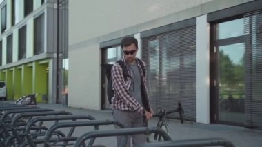 Güvenlik ve hırsızlığa karşı bisiklet kilidi. Erkek bisikletçi, Almanya 'nın Avrupa kentindeki bisiklet parkında bisiklet kilitliyor. Adam bisikletin çalınmasını önlemek için kilidi ve askıyı açıyor.